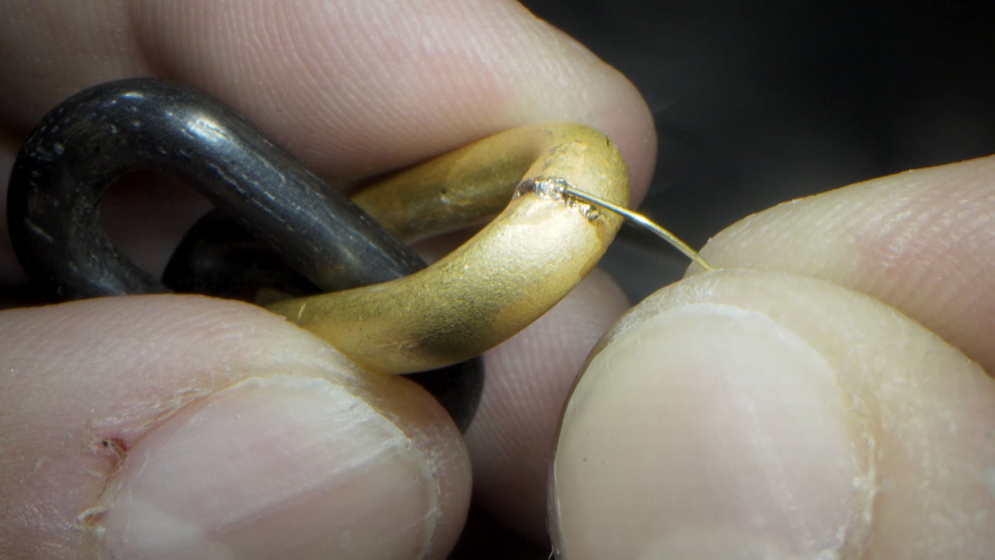 Close-up of filler wire welding on an ebony and gold bracelet